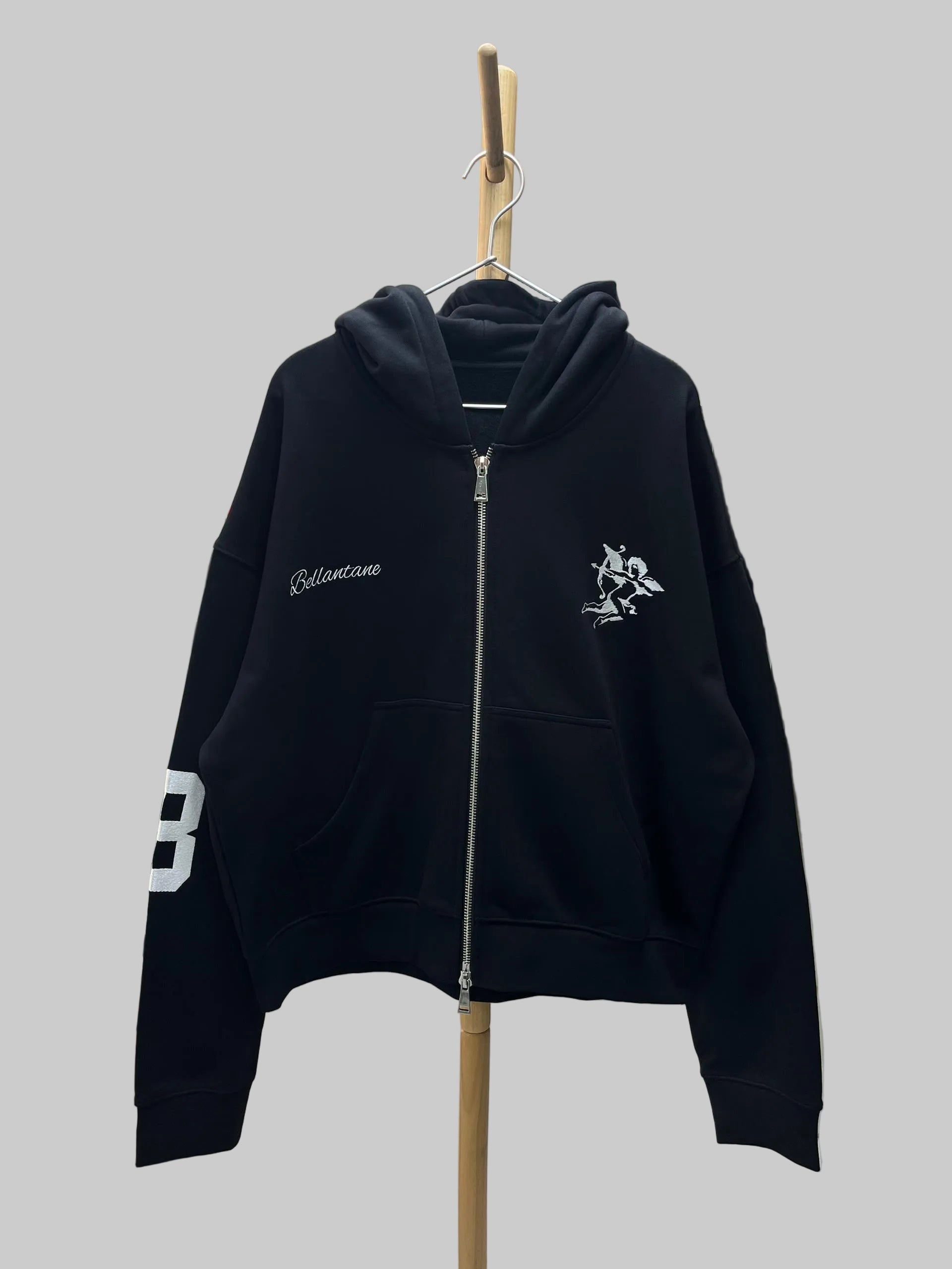 Black hoodie with white branding on a hanger in a store setting